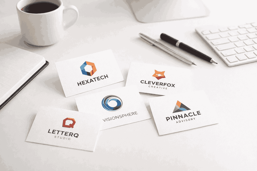 Minimalist white desk with creative logo design business cards, coffee cup, pens, and notebook in modern workspace